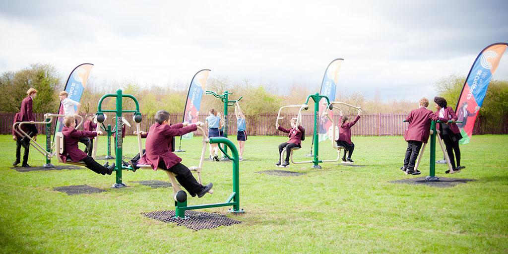 secondary school children using outdoor gym equipment